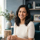 A friendly South Asian mother smiling warmly, representing a satisfied customer in a professional, modern setting.